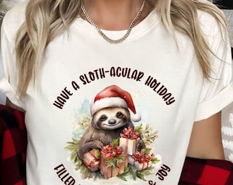 May include: Cream-colored t-shirt with a sloth wearing a Santa hat and holding gifts. The text reads "Have a Sloth-acular Holiday Filled with Relaxation & Joy". The sloth is surrounded by greenery and red flowers.