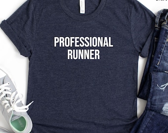 Puede incluir: Camiseta azul marino jaspeado con el texto "PROFESSIONAL RUNNER" en blanco. La camiseta se combina con un par de zapatillas grises y vaqueros azules. La camiseta está hecha de un material suave y cómodo.
