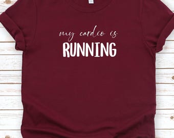 Puede incluir: Camiseta granate con mangas enrolladas. La camiseta presenta el texto "my cardio is RUNNING" en blanco, una declaración humorística para corredores. La camiseta está hecha de un material suave y es adecuada para ropa casual.