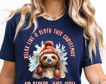 May include: Navy blue t-shirt featuring a sloth wearing a red and brown knit hat. The text on the shirt reads "Relax like a sloth this Christmas" and "No stress, just chill". The design includes a watercolor-style illustration of a sloth.