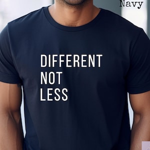Könnte beinhalten: Marineblaues T-Shirt mit den weißen Worten "DIFFERENT NOT LESS". Das Shirt hat kurze Ärmel und einen Rundhalsausschnitt. Das Wort "Navy" ist oben rechts aufgedruckt.