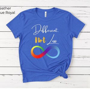 May include: A true royal blue t-shirt with the text "Different, Not Less" in white script and a rainbow infinity symbol. The shirt is made of a soft material and has a classic crew neck.