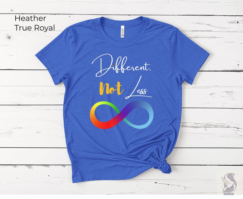 May include: A true royal blue t-shirt with the text "Different, Not Less" in white script and a rainbow infinity symbol. The shirt is made of a soft material and has a classic crew neck.