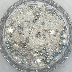 May include: A glass bowl filled with white and blue sprinkles, sugar crystals, and pearl-like sprinkles. The sprinkles are ideal for decorating cakes, cupcakes, and other desserts.
