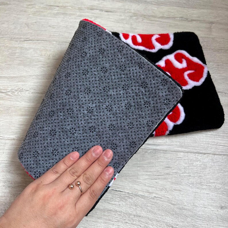 Hand-tufted anime keyboard rug with red cloud pattern on black background.