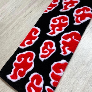 Hand-tufted anime keyboard rug with red cloud pattern on black background.