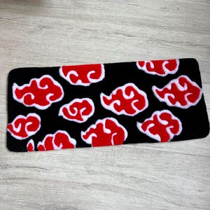 Hand-tufted anime keyboard rug with red cloud pattern on black background.
