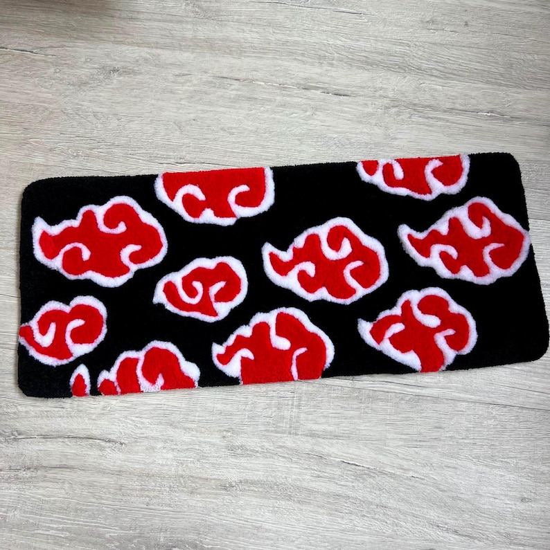 Hand-tufted anime keyboard rug with red cloud pattern on black background.