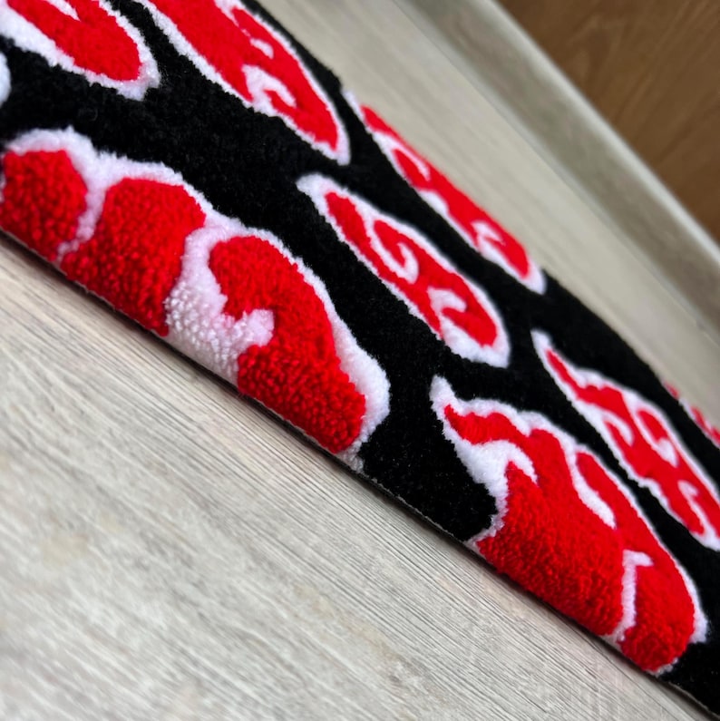 Hand-tufted anime keyboard rug with red cloud pattern on black background.