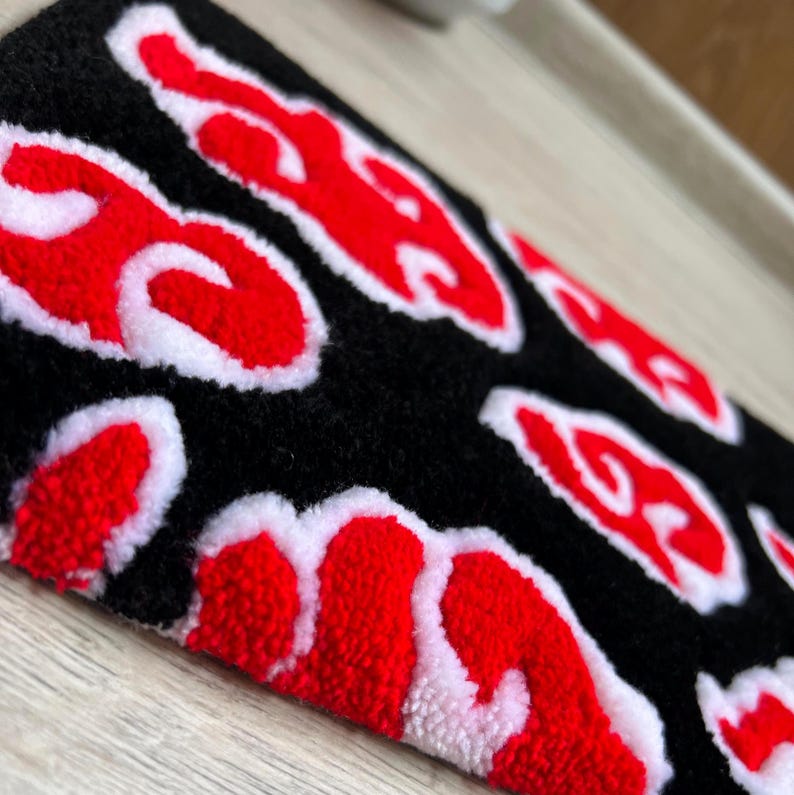 Hand-tufted anime keyboard rug with red cloud pattern on black background.