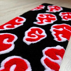 Hand-tufted anime keyboard rug with red cloud pattern on black background.