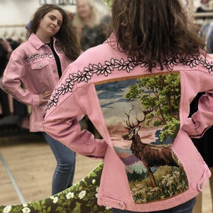 Puede incluir: Una taza de cerámica blanca con asa negra y el texto "But First, Coffee" en negrita negra. La taza se encuentra sobre un fondo borroso, sugiriendo un ambiente acogedor.