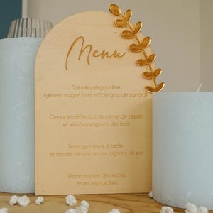 Peut inclure: Une pancarte de menu en bois avec un motif de feuille d'or. Le menu comprend : Salade périgourdine (gésiers, magret fumé et foie gras de canard), Grenadin de veau à la crème de cèpes et ses champignons des bois, Fromages servis à table et salade de mâche aux pignons de pin, Pièce montée des mariés et ses mignardises.