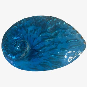 May include: A blue, nautilus-shaped decorative object. The object has a glossy, textured surface with swirling patterns. The color is a deep, vibrant blue, and the overall shape is reminiscent of a seashell.