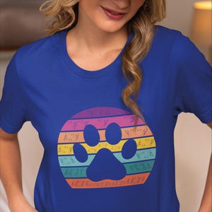 May include: A royal blue t-shirt with a rainbow paw print design. The paw print is surrounded by a circle of musical notes.