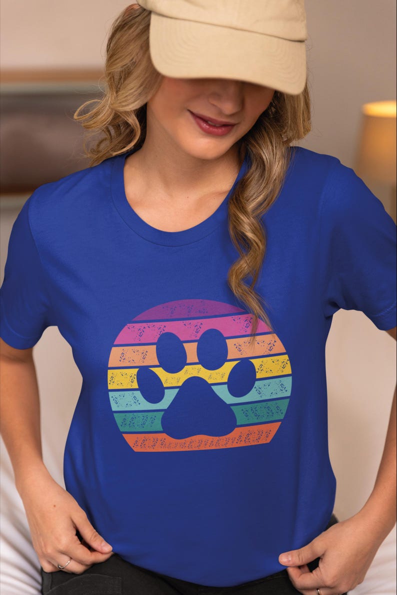 May include: A royal blue t-shirt with a rainbow paw print design. The paw print is surrounded by a circle of musical notes.