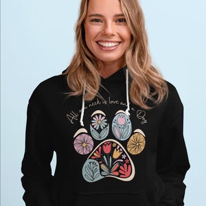 May include: Black hoodie with a floral paw print design and the text "All you need is love and a Dog".