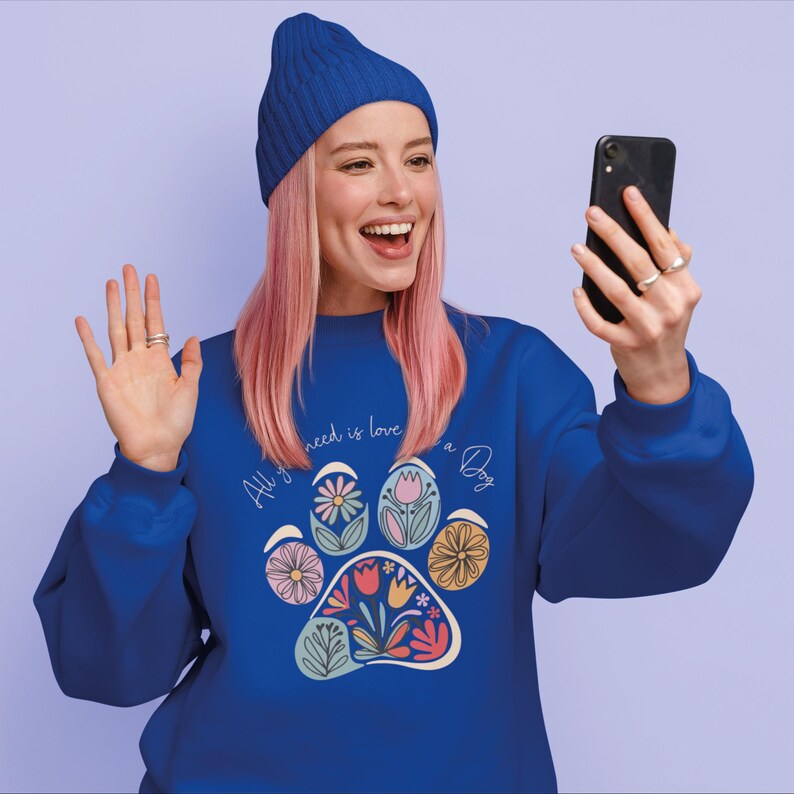 May include: A blue sweatshirt with a paw print design featuring colorful flowers and the text "All you need is love and a Dog".