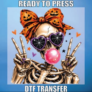 May include: A graphic design featuring a skeleton wearing a large orange bow with jack-o'-lantern faces, purple heart-shaped sunglasses with spiderweb patterns, and blowing a pink bubble. The skeleton makes peace signs with both hands. Text reads READY TO PRESS DTF TRANSFER.