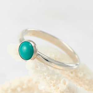 Puede incluir: Un anillo de plata con una piedra turquesa engastada en un engaste de bisel.