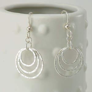 May include: Silver dangle earrings with three hammered circles.