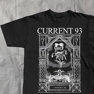 Könnte beinhalten: Schwarzes T-Shirt mit weißer Grafik. Die Grafik zeigt den Text "CURRENT 93" über einer detaillierten Illustration einer Blume in einem bogenförmigen Rahmen, mit dem Wort "IMPERIUM" unten. Das Design hat eine gotische oder Vintage-Ästhetik.