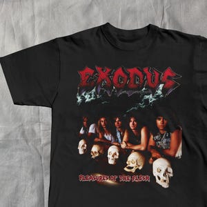 Könnte beinhalten: Schwarzes T-Shirt mit dem Bandlogo von Exodus in Rot und Weiß. Das Shirt zeigt eine Gruppe von Bandmitgliedern und Totenköpfen. Der Text "PLEASURES OF THE FLESH" ist unter den Totenköpfen und Bandmitgliedern aufgedruckt.