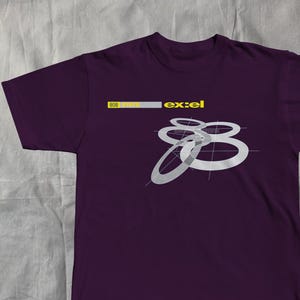 以下が含まれることがあります： 濃い紫色のTシャツ。黄色と白で「ex:el」の文字がプリントされています。白のリングが重なり合ったグラフィックが特徴です。「808」の文字も黄色で見えます。