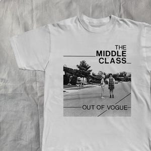 Peut inclure: T-shirt blanc avec une image en noir et blanc de deux personnes dans la rue. Le texte "THE MIDDLE CLASS" est au-dessus de l'image et "OUT OF VOGUE" en dessous.