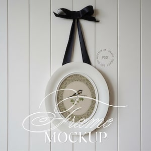 Peut inclure: Un cadre photo ovale blanc avec un ruban noir pour le suspendre. Le cadre contient une illustration d'un petit oiseau posé sur une branche sur un fond beige à motifs. Le texte MOCKUP 4K SMART OBJECT 300 DPI PSD est visible sur l'image.
