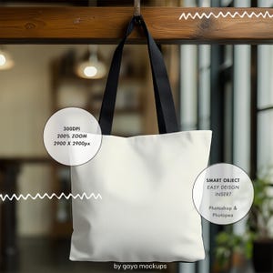 May include: White tote bag mockup with black handles hanging from a wooden surface. The bag has a smart object for easy design insertion using Photoshop or Photopea. The image is 2900 x 2900 pixels at 300 DPI.