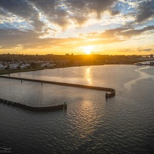 The warm yellow sun rises above the horizon, its light reflecting on the water near the entrance to the Benicia Marina.