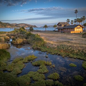 The clouds reflect in the still waters of the Benicia Marsh, while the historic depot building stands in the background.