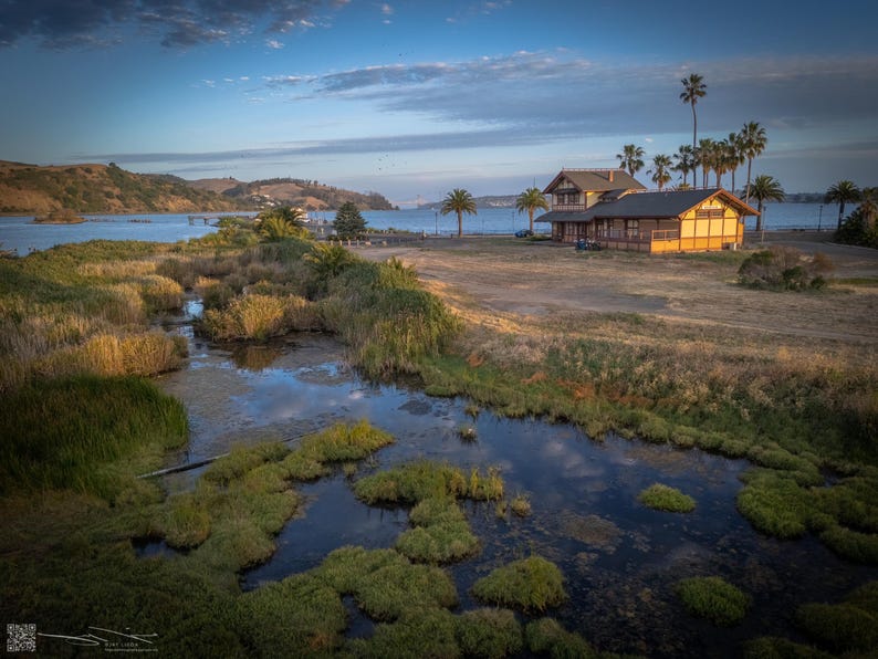 The clouds reflect in the still waters of the Benicia Marsh, while the historic depot building stands in the background.