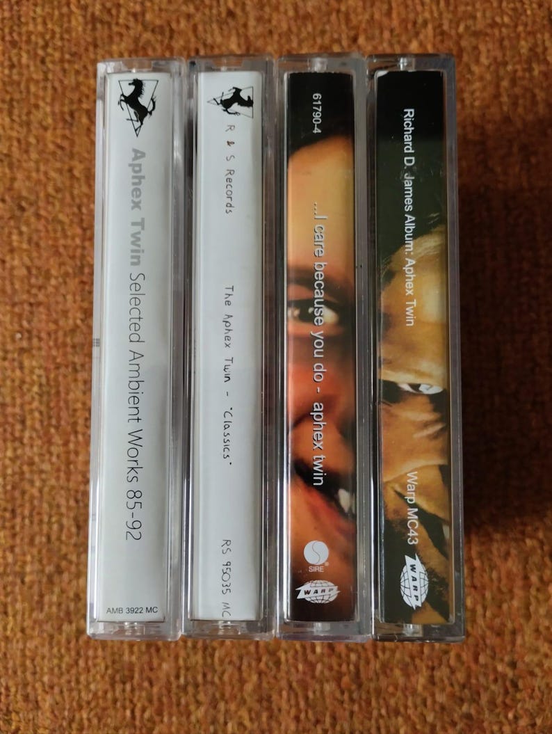 May include: Four cassette tapes with white and black labels. The labels include the text "Aphex Twin Selected Ambient Works 85-92", "The Aphex Twin - "Classics", "...I care because you do - aphex twin", and "Richard D. James Album: Aphex Twin".