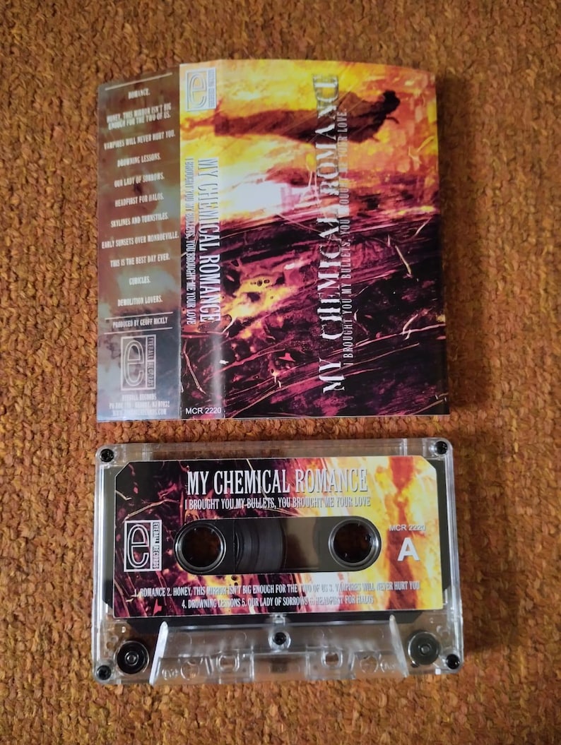 May include: A cassette tape and its case featuring the album art for "I Brought You My Bullets, You Brought Me Your Love" by My Chemical Romance. The case has a red and orange design with the band's name. The cassette tape is clear.