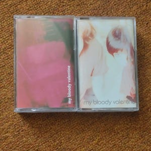 以下が含まれることがあります： 前面に「my bloody valentine」というバンド名が印刷されたカセットテープが2つ。左側のテープはピンクと白の抽象的なデザイン。右側のテープは2人のぼやけた画像です。