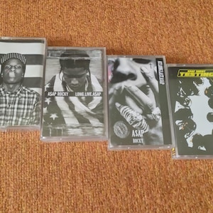 Puede incluir: Cuatro cintas de cassette con cubiertas en blanco y negro. Las cubiertas muestran el nombre del artista y el título del álbum. Los títulos de los álbumes son "Long.Live.A$AP", "Testing" y "A$AP Rocky".
