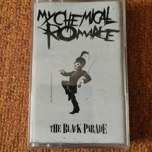 May include: A cassette tape case featuring a black and white illustration of a cartoon skeleton in military attire. The text "My Chemical Romance" is printed in black at the top of the case. The text "The Black Parade" is printed in black at the bottom of the case.