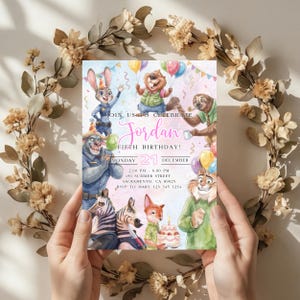 Pode incluir: Um convite de anivers&aacute;rio colorido com personagens de animais de desenho animado. O convite inclui o texto "JOIN US TO CELEBRATE Jordan FIFTH BIRTHDAY!" com a data, hora e detalhes do local. O convite &eacute; segurado por m&atilde;os e rodeado por uma coroa de flores.