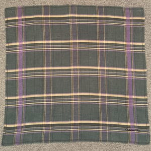 May include: A square, plaid handkerchief in shades of gray, purple, and tan. The pattern features intersecting lines creating a grid design. The lower right corner has the text "Christian Dior".