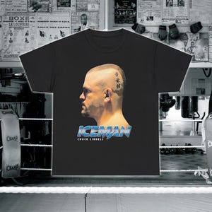 Puede incluir: Camiseta negra con un gráfico de Chuck Liddell, un luchador de artes marciales mixtas, con el texto "ICEMAN CHUCK LIDDELL". El gráfico está en un esquema de color azul y blanco y presenta un diseño de rayo.