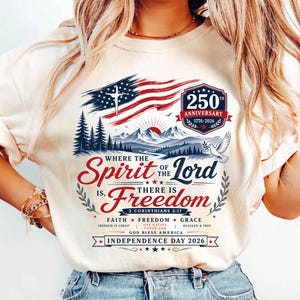 May include: A cream-colored t-shirt featuring a graphic of the American flag, mountains, and a dove. Text includes 250 Anniversary 1776-2026, Where the Spirit of the Lord is, there is Freedom, 2 Corinthians 3:17, Faith, Freedom, Grace, and Independence Day 2026.