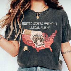 May include: Dark gray t-shirt with the text "UNITED STATES WITHOUT ILLEGAL ALIENS" above a map of the United States. The map is colored in shades of red and brown, with tribal names. The shirt is a vintage style.