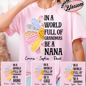 May include: A light pink t-shirt with the text "IN A WORLD FULL OF GRANDMAS BE A NANA" and a colorful daisy design. The daisy has petals in various patterns and colors. The shirt also has the names "Emma Sophia David" below the text.