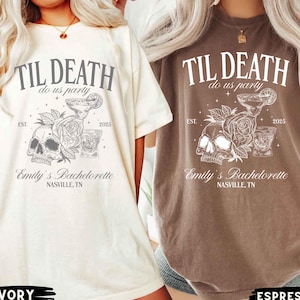 K&ouml;nnte beinhalten: Elfenbein- und espressofarbene T-Shirts mit dem Text "TIL DEATH do us party" und "Emily's Bachelorette NASVILLE, TN." Die Shirts zeigen Sch&auml;del-, Rosen- und Cocktailgrafiken. Das Jahr "2025" ist ebenfalls aufgedruckt.