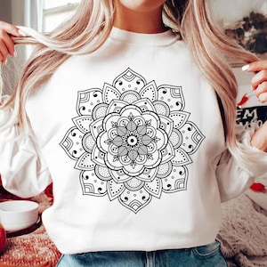 Pode incluir: Uma camisa de moletom branca com um design de mandala preto e branco estampado na frente.