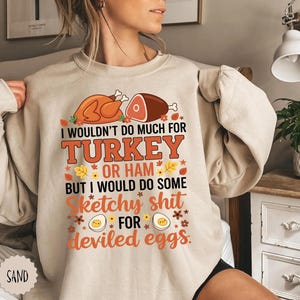 May include: Beige sweatshirt with the text "I wouldn't do much for turkey or ham but I would do some sketchy shit for deviled eggs." The graphic includes images of a turkey, ham, and deviled eggs.