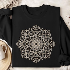 May include: Black long-sleeved shirt with a gold mandala design featuring the words "RESIST" and "FDT" repeated around the circle.