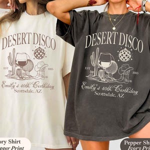 May include: Two t-shirts, one ivory and one pepper, featuring a desert-themed graphic. The design includes the text "DESERT DISCO," a cactus, wine glass, cowboy hat, and the text "Emily's 40th Birthday Scottsdale, AZ."